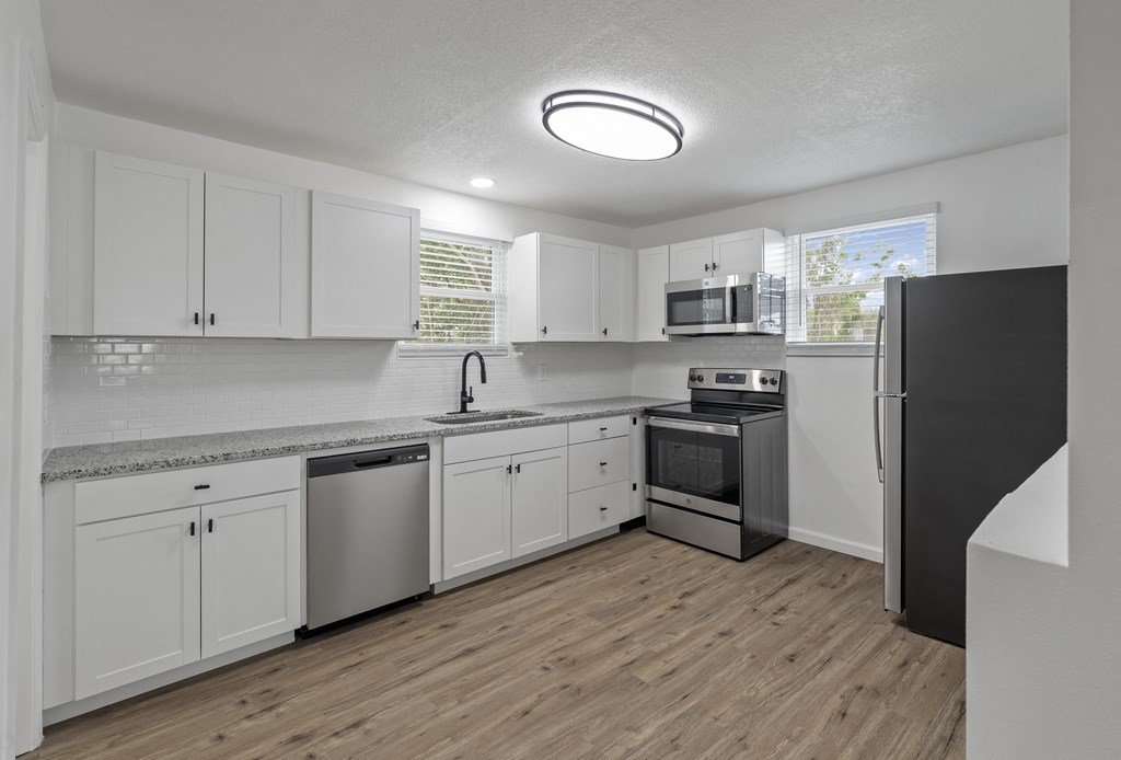 an empty kitchen with white cabinets and stainless steel appliances
