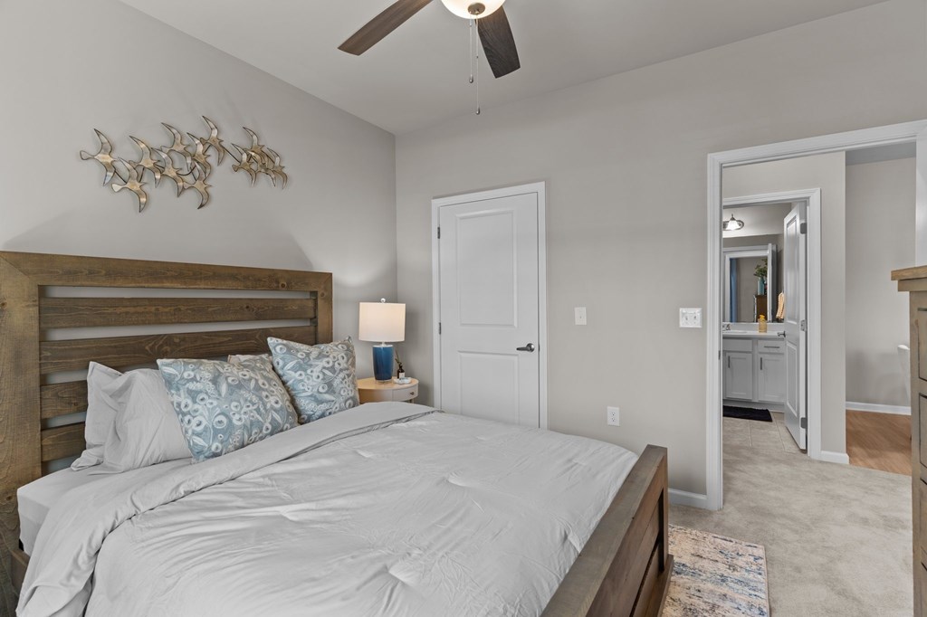 A bedroom with a bed, a ceiling fan, and a mirror.