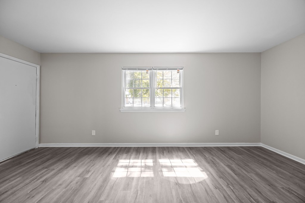 A room with a window and wooden flooring.
