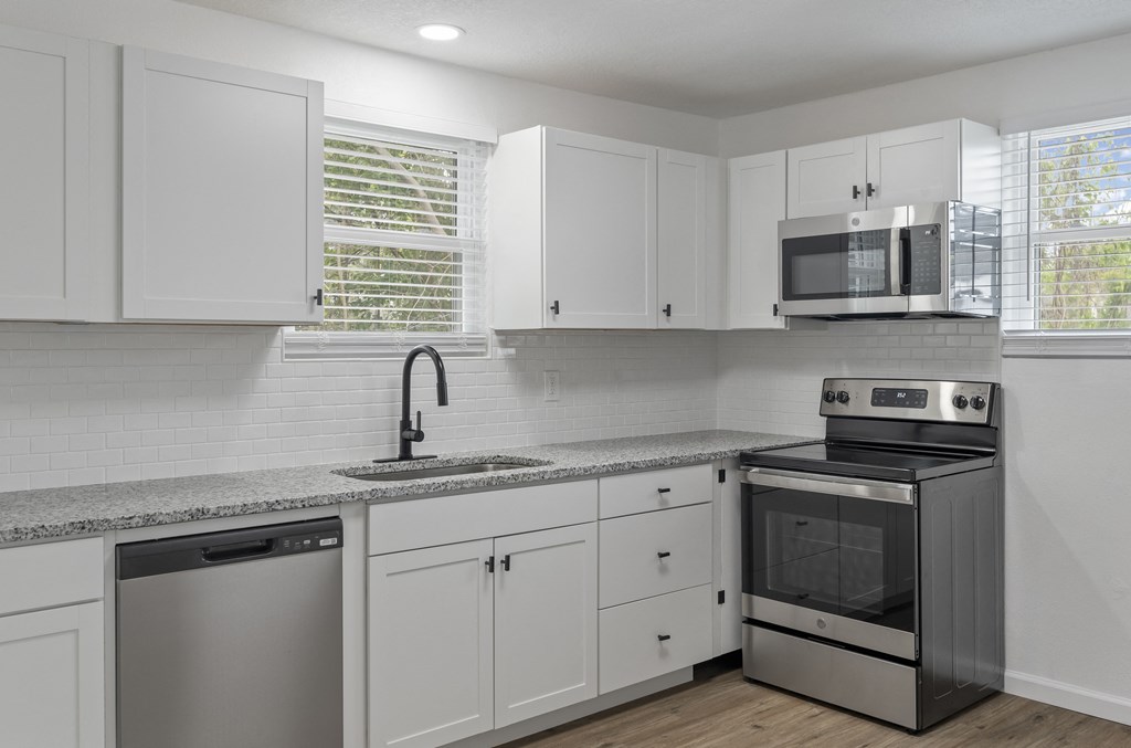 a kitchen with white cabinets and stainless steel appliances