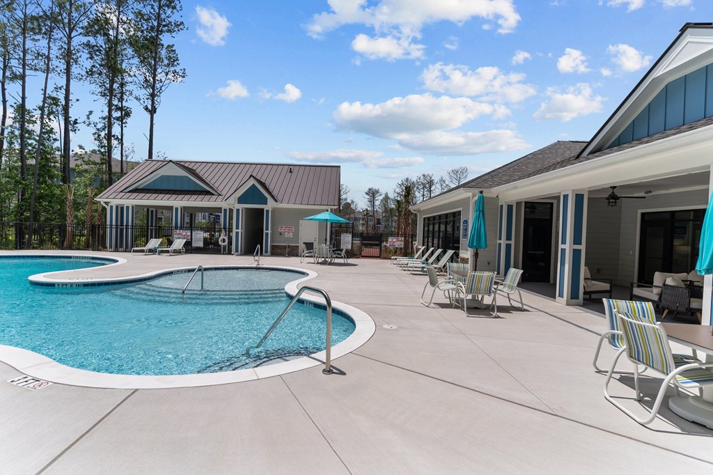 A large outdoor swimming pool with a slide and lounge chairs.