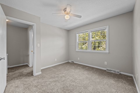 A room with a ceiling fan and a window.