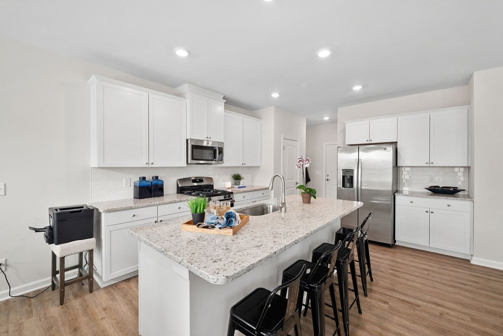a kitchen with white cabinets and a marble counter top