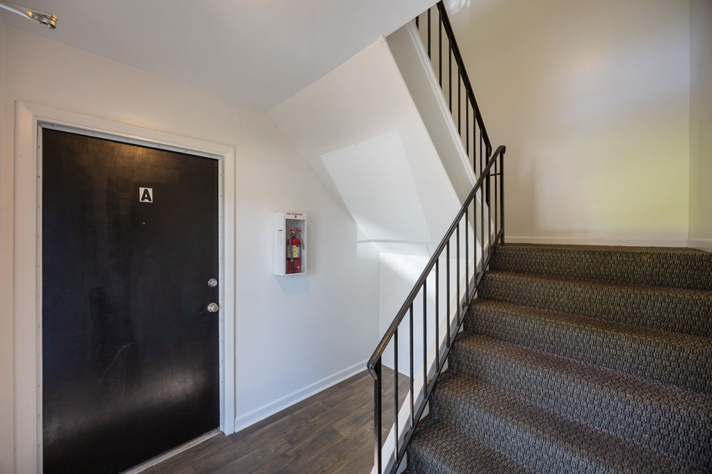 A staircase with a black door and a fire extinguisher on the wall.