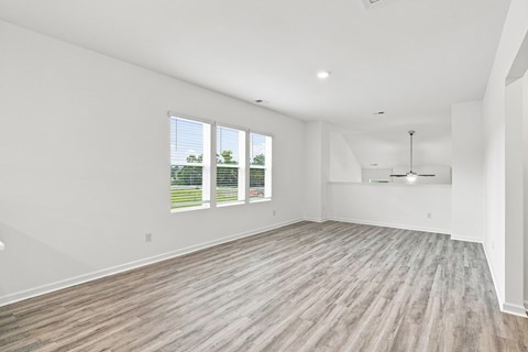 A spacious room with wooden flooring and large windows.