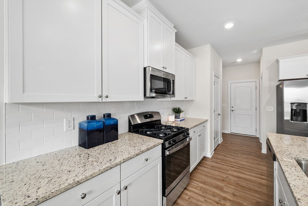 a renovated kitchen with white cabinets and granite counter tops
