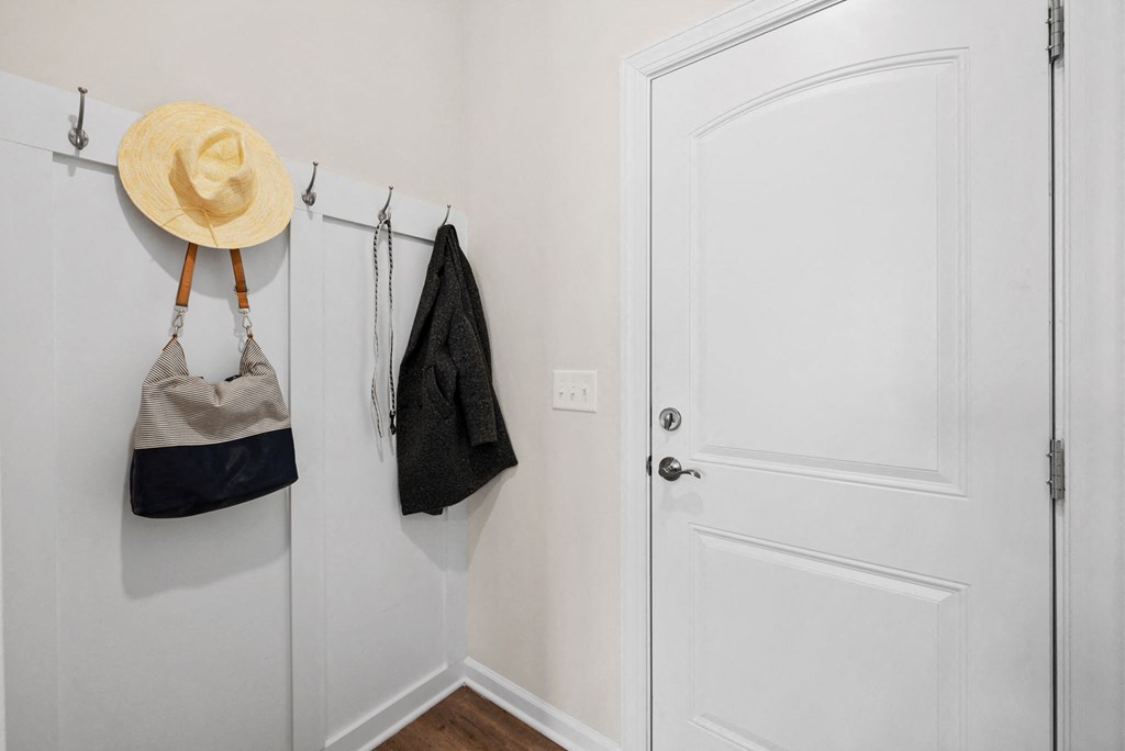 a closet with a white door and two bags and a hat hanging on the wall