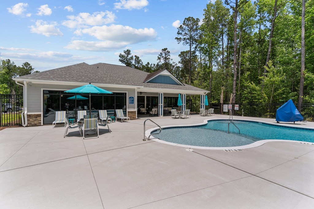 A pool and patio area with a gazebo and lounge chairs.
