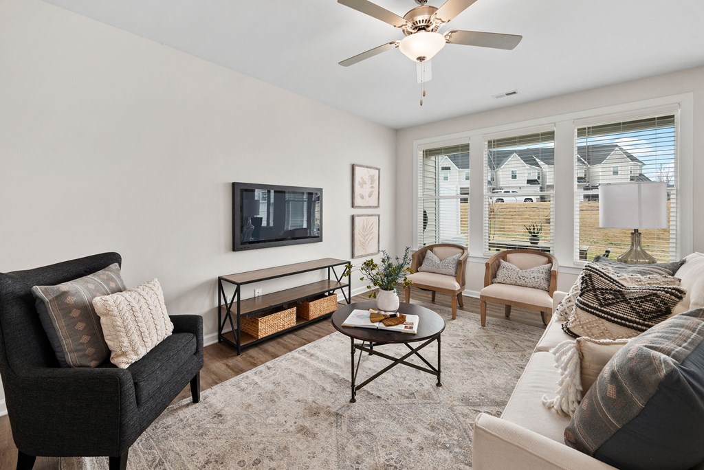 a living room with a ceiling fan and a television