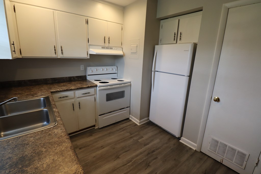 A kitchen with a white fridge and white cabinets.