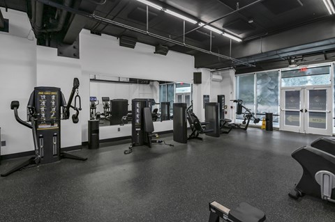 A gym with a variety of equipment including treadmills, weights, and exercise machines.
