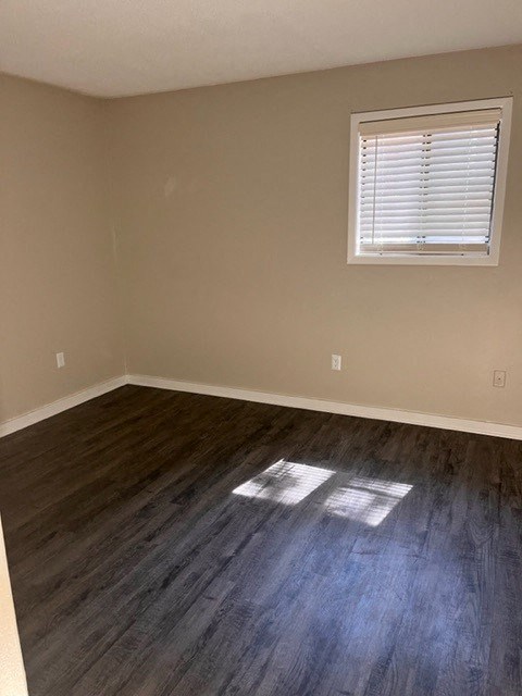 an empty room with a window and wooden floors