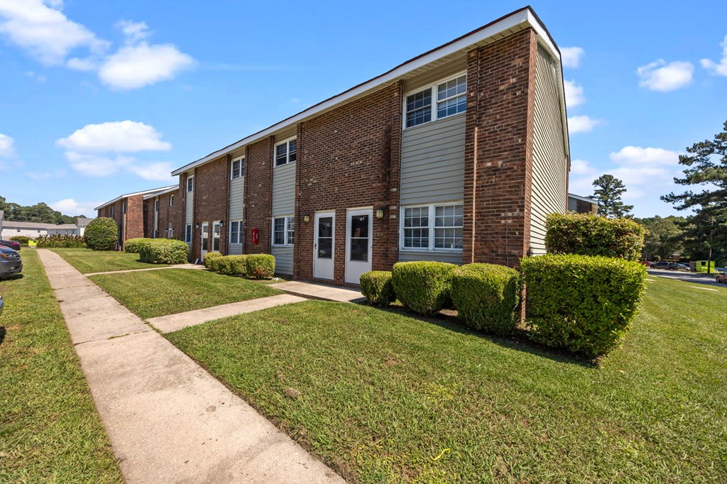 A long brick building with a white door and windows.