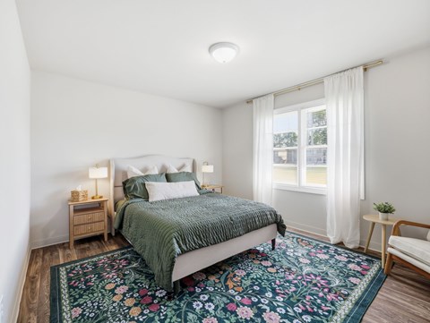 A bedroom with a bed, nightstands, and a rug.