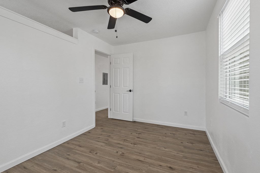 an empty bedroom with white walls and a ceiling fan