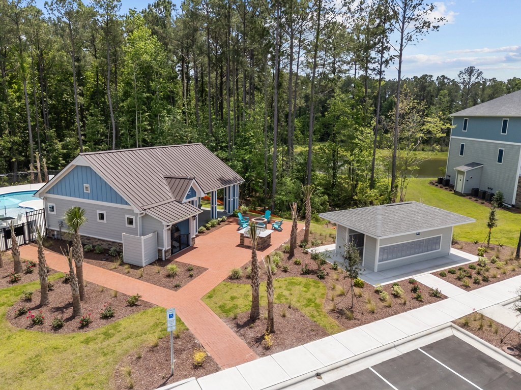 A house with a grey roof is surrounded by trees and has a parking lot in front.