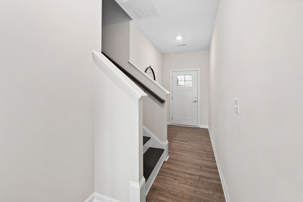 a living room with white walls and white stairs and a white door