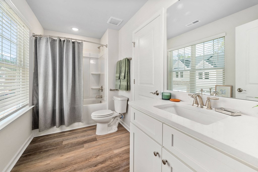 a bathroom with a white sink and toilet and a gray shower curtain