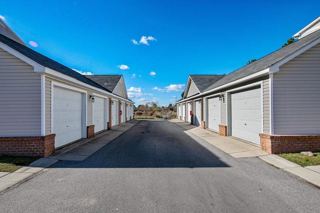 a row of houses with white garage doors on the side of a street