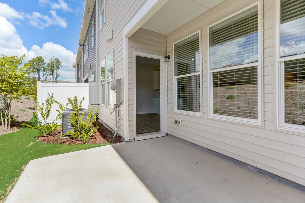 the front porch of a white house with a concrete driveway