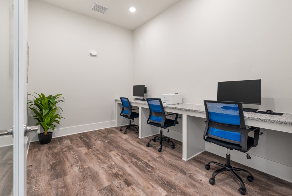 three desks with computers and blue chairs in a room
