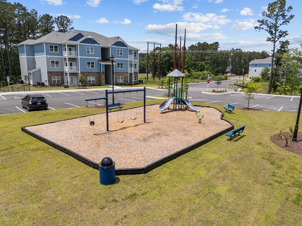 A playground with a slide and swings in front of a large building.