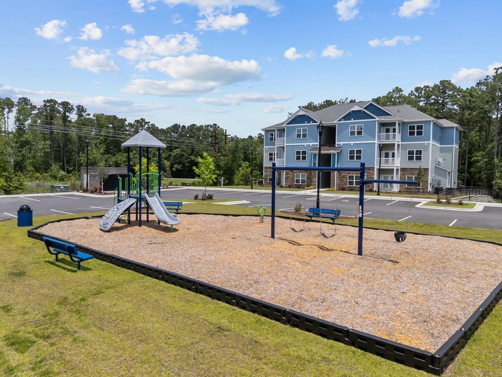 A playground with a slide and a swing set in front of a large building.
