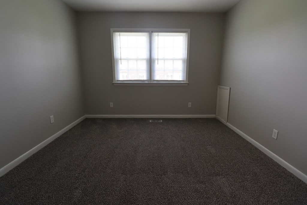 A room with a carpeted floor and a window.