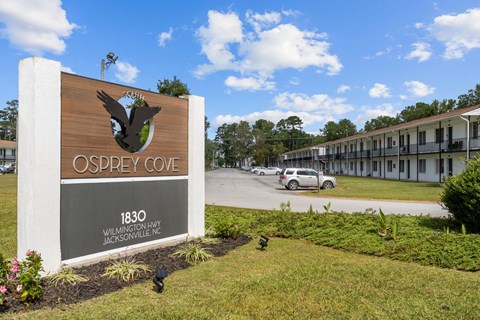 A sign for Osprey Cove is in front of a building.