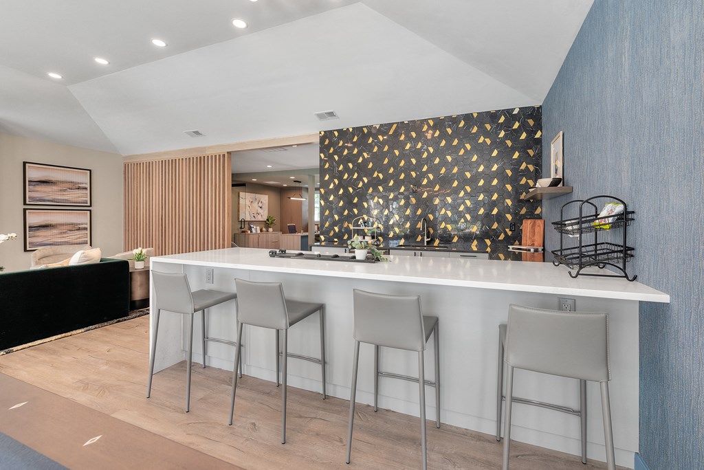 a kitchen with a white counter top and three stools