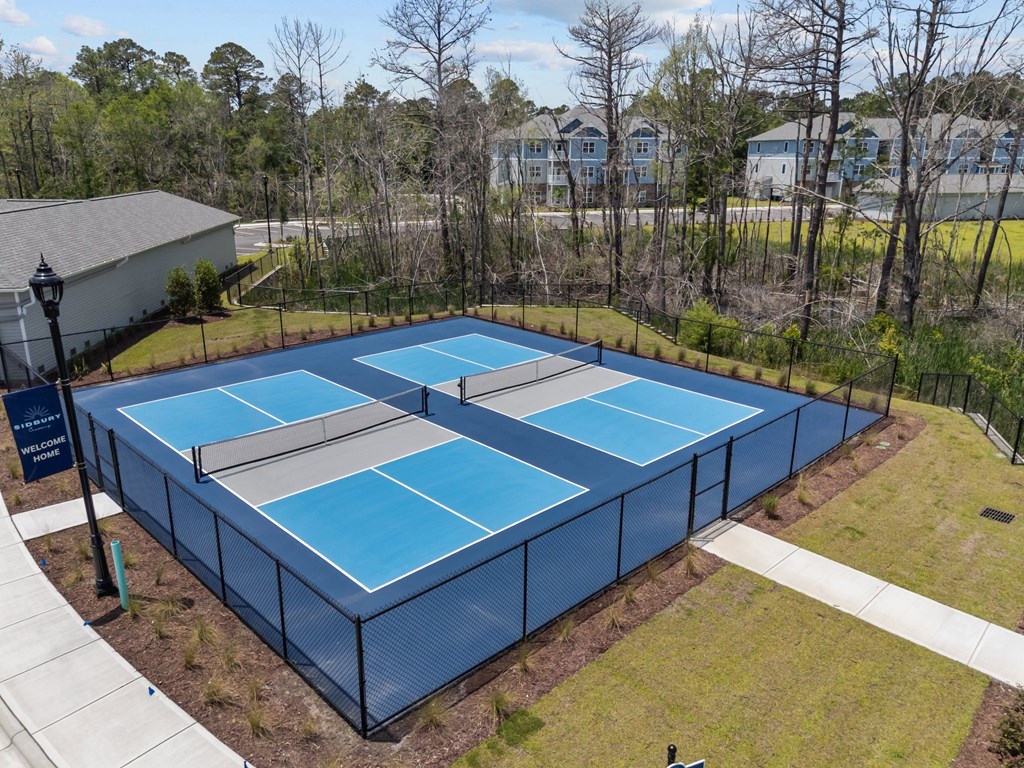 A tennis court surrounded by a fence and trees.