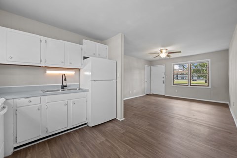 A kitchen with white cabinets and a wooden floor.