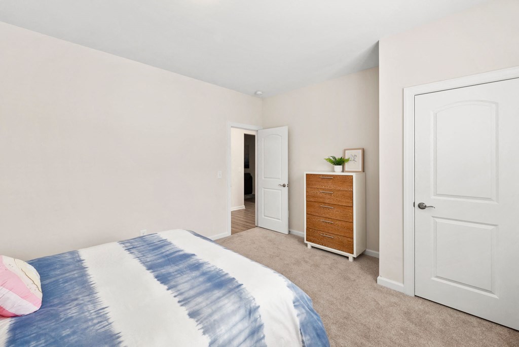 a bedroom with a bed and a dresser and a door to a hallway