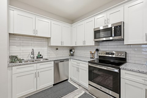 A kitchen with white cabinets and a black stove top oven.