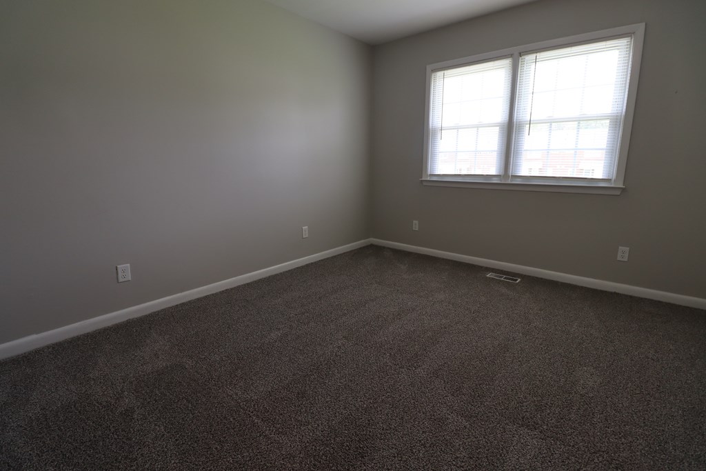 A room with a carpeted floor and a window.