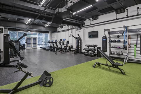 A gym with a variety of equipment including a rowing machine, weights, and a bench press.