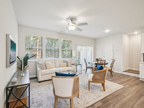A living room with a white couch, a wooden table, and a ceiling fan.