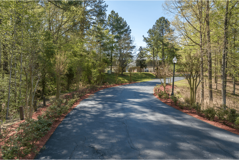 a road with trees on both sides and a building in the background