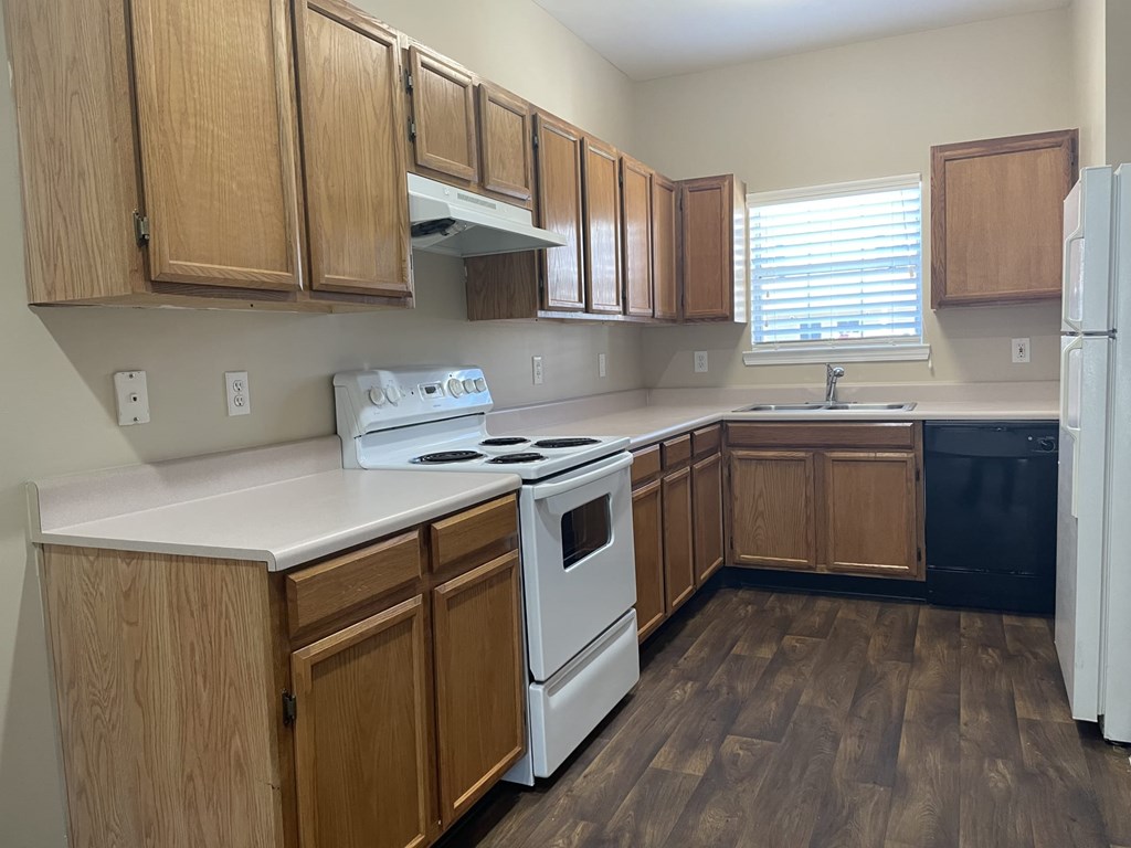 A kitchen with wooden cabinets and a white stove top oven.