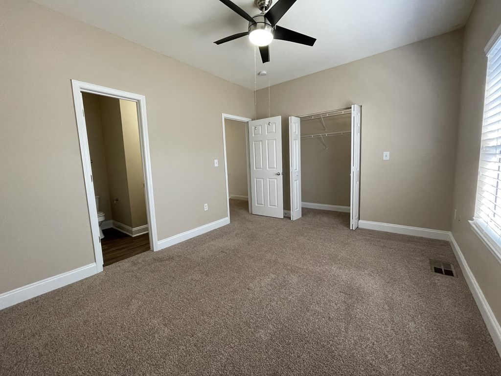 A room with a ceiling fan and carpeted floor.