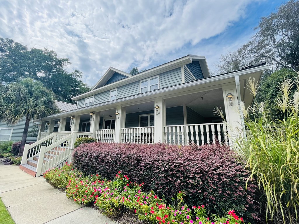 A house with a grey roof and white walls with a porch and a white railing.