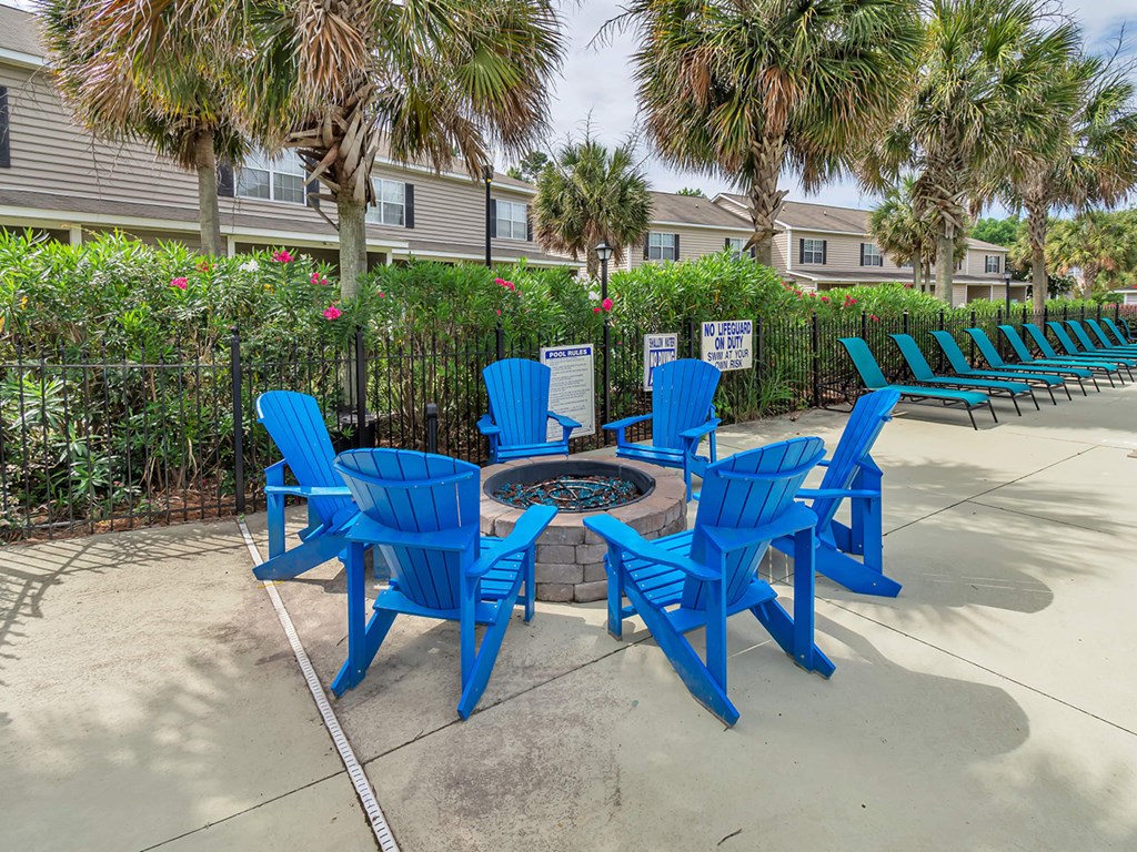 A set of blue chairs and a table are arranged in a circle on a patio.