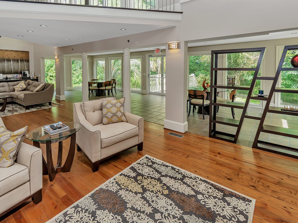 A living room with a white sofa, a glass coffee table, and a rug with a floral pattern.