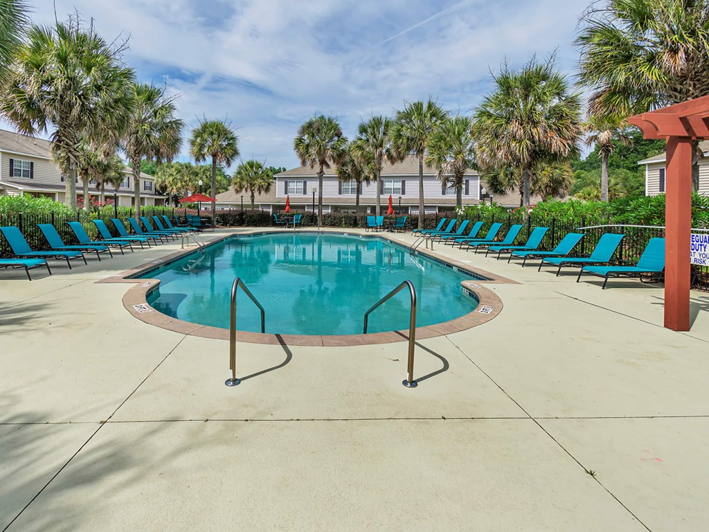 A large swimming pool surrounded by palm trees and lounge chairs.