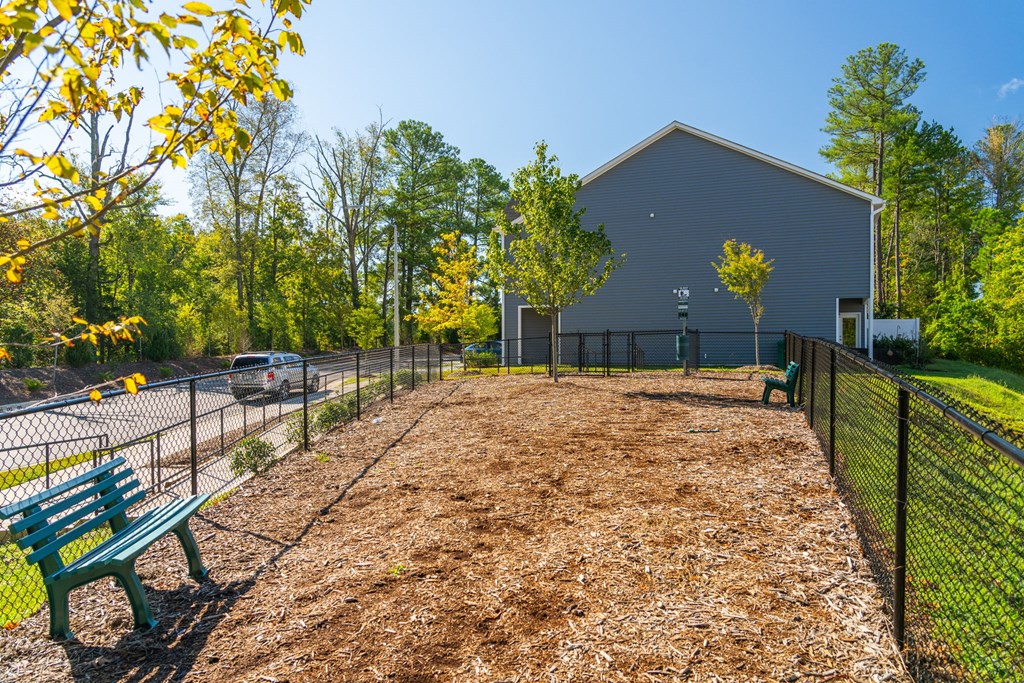 a fenced in dog park with a bench and a fence