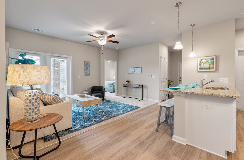 a living room and kitchen area with a ceiling fan and a blue rug