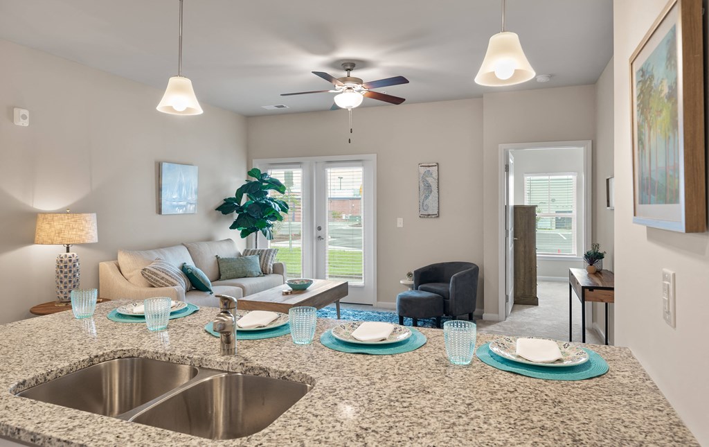 a kitchen and living room with a large island with a granite countertop and a ceiling fan