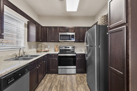 A kitchen with dark wood cabinets and stainless steel appliances.