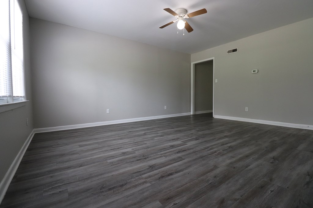 A room with a ceiling fan and wooden flooring.