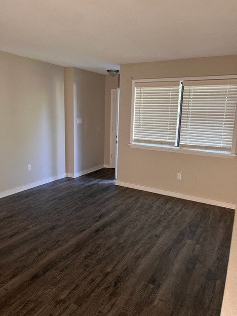 an empty living room with a large window and wooden floors